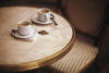 Image of 2 coffee cups on a table with coins.